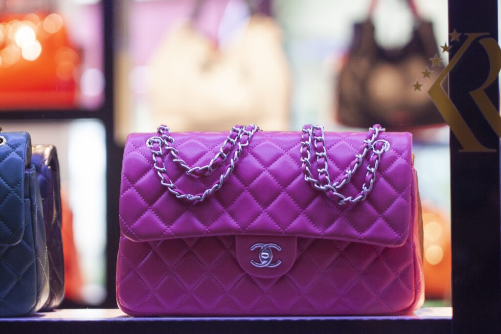 Sac à main matelassé rose vif avec chaîne argentée exposé dans une vitrine lumineuse.