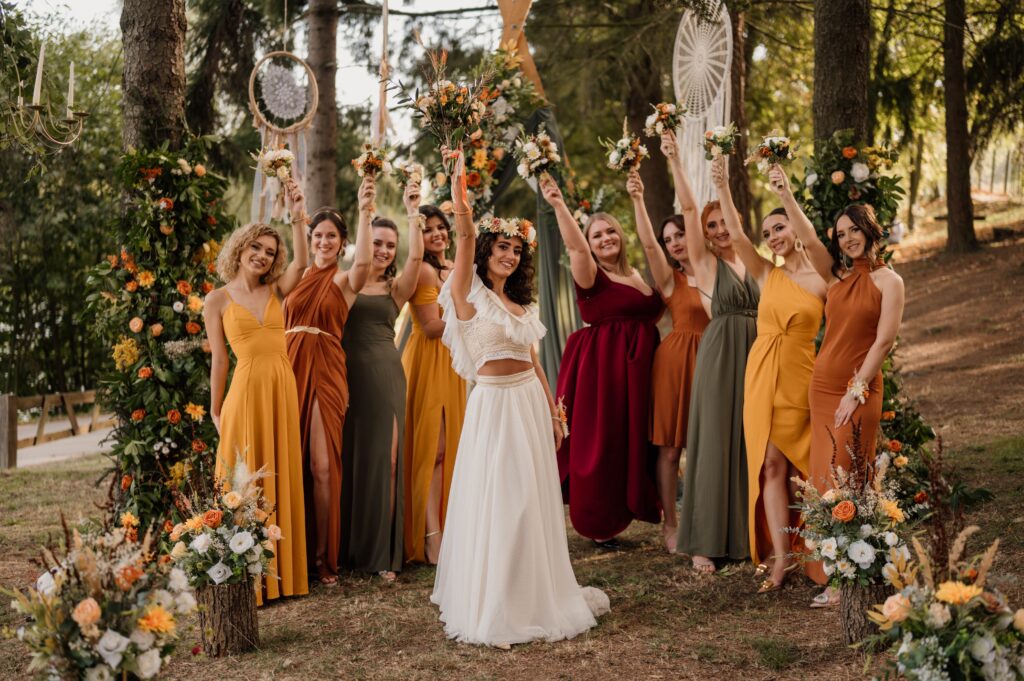 Une mariée entourée de ses demoiselles d'honneur en robes colorées, levant joyeusement leurs bouquets.