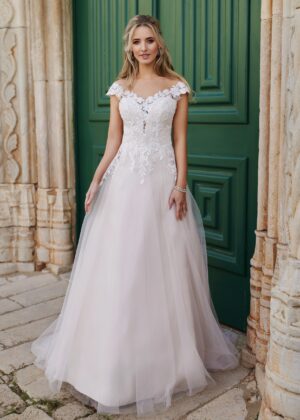 Robe de mariée avec corsage en dentelle florale et jupe évasée en tulle, devant une porte verte imposante pour un cadre bohème et chic