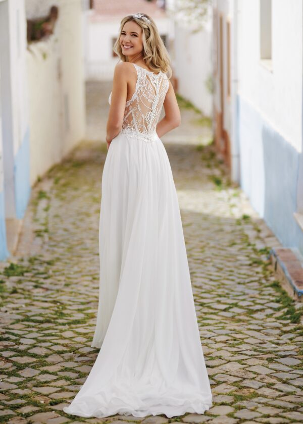 Robe de mariée fluide avec dos en dentelle transparente, modèle en promenade dans une ruelle pavée