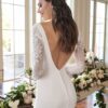 Robe de mariée avec un dos plongeant et des manches en dentelle dans une salle lumineuse décorée de fleurs