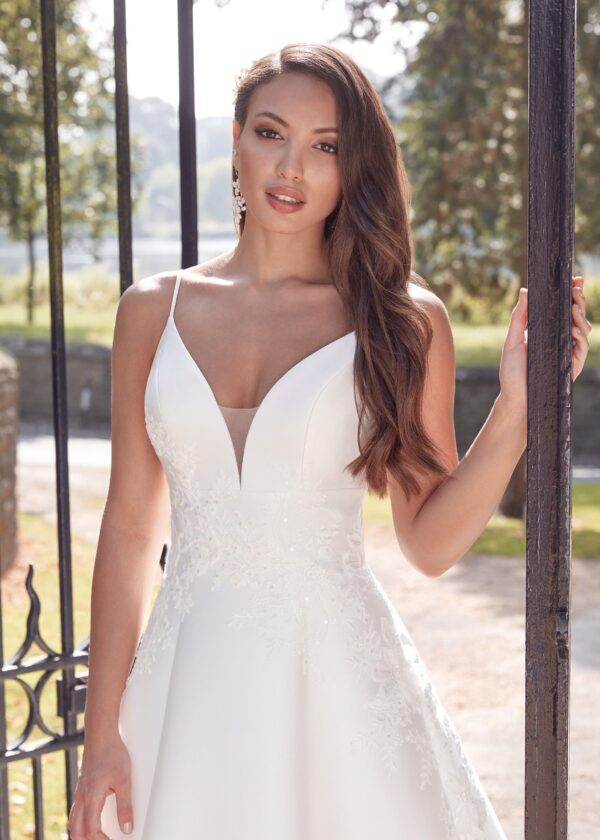 Femme en robe de mariée blanche près d'une grille en fer forgé