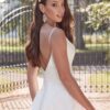 Mariée de dos portant une robe de mariée avec décolleté plongeant, en extérieur près d'une grille