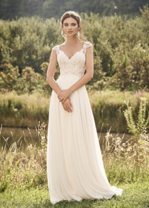 Robe de mariée en dentelle champêtre devant un paysage verdoyant