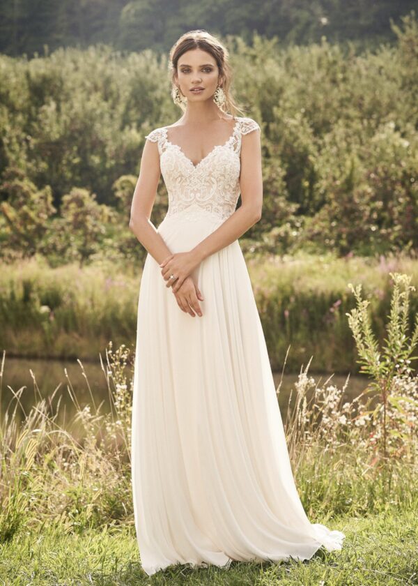 Robe de mariée en dentelle champêtre devant un paysage verdoyant
