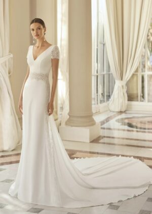 Mariée en robe de mariée élégante avec manches courtes en dentelle et une longue traîne, dans une salle lumineuse