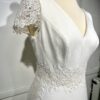 Mariée en robe de mariée élégante avec manches courtes en dentelle et une longue traîne, dans une salle lumineuse