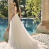 Mariée de dos en robe de mariée avec dos plongeant, posant près d'une piscine dans un cadre romantique en plein air
