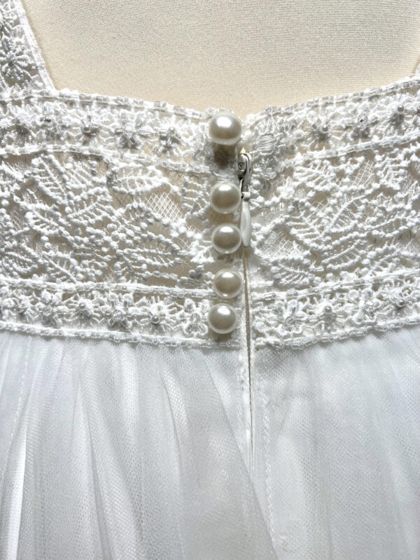Mariée posant élégamment en robe de mariée avec un décolleté en V profond près d'une piscine, dans un cadre romantique en extérieur