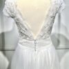 Mariée en robe de mariée avec corsage en dentelle et fente latérale, posant devant des colonnes en pierre