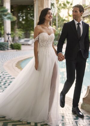 Couple élégant lors d'une cérémonie de mariage, la mariée en robe blanche à épaules dénudées avec une fente élégante, et le marié en costume noir classique près d'une piscine