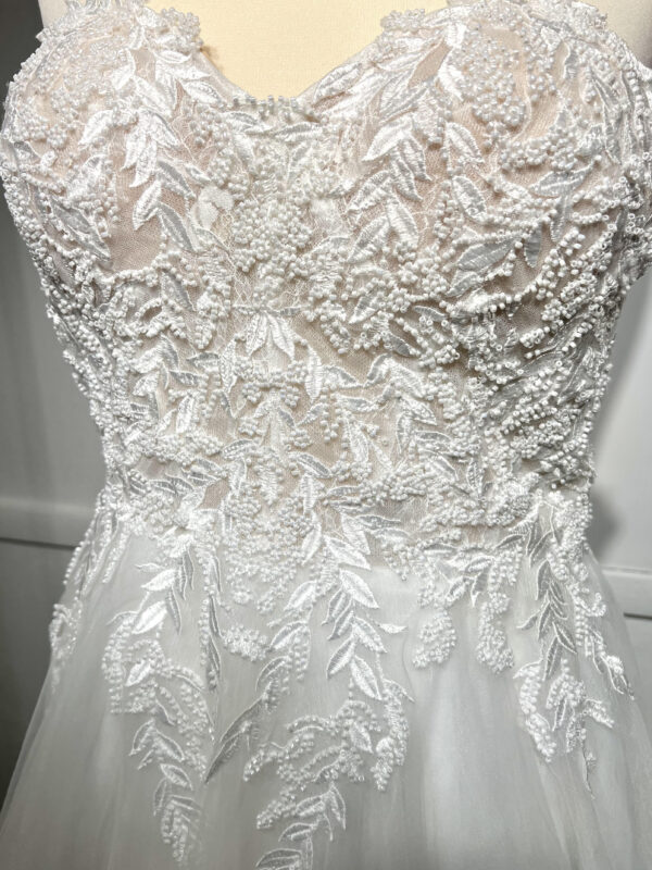 Couple élégant lors d'une cérémonie de mariage, la mariée en robe blanche à épaules dénudées avec une fente élégante, et le marié en costume noir classique près d'une piscine