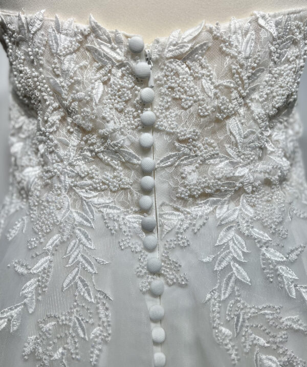 Couple élégant lors d'une cérémonie de mariage, la mariée en robe blanche à épaules dénudées avec une fente élégante, et le marié en costume noir classique près d'une piscine