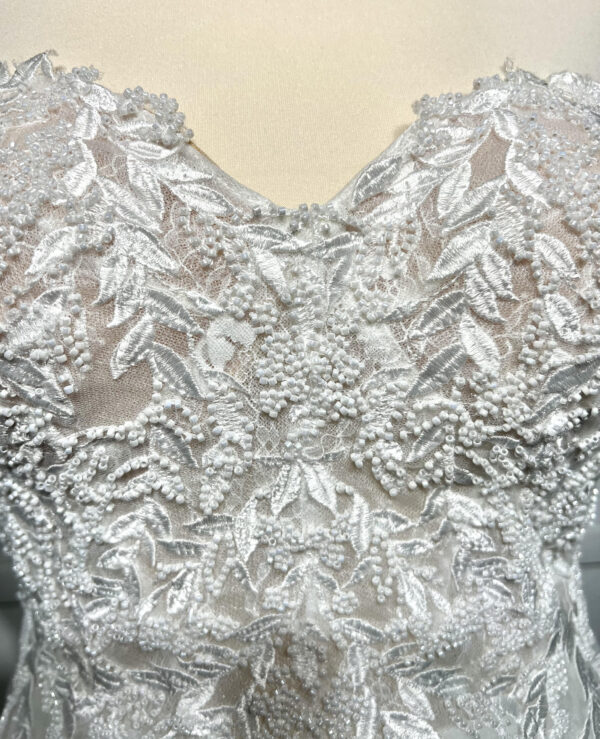 Couple élégant lors d'une cérémonie de mariage, la mariée en robe blanche à épaules dénudées avec une fente élégante, et le marié en costume noir classique près d'une piscine