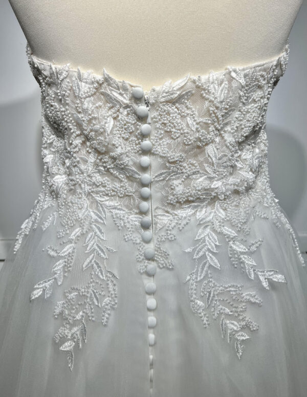 Couple élégant lors d'une cérémonie de mariage, la mariée en robe blanche à épaules dénudées avec une fente élégante, et le marié en costume noir classique près d'une piscine