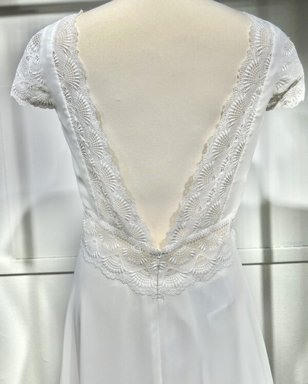 Vue de face d'une mariée en robe blanche à manches courtes et encolure en V ornée de dentelle délicate