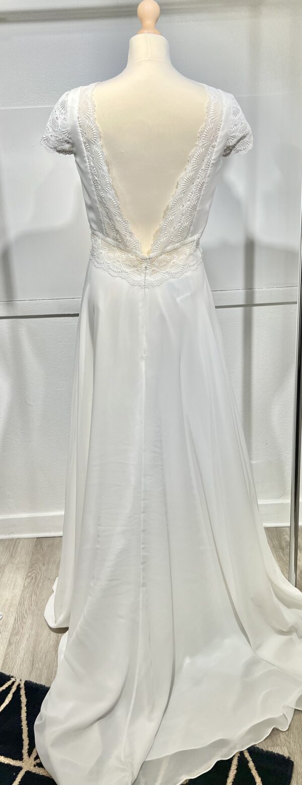 Vue de face d'une mariée en robe blanche à manches courtes et encolure en V ornée de dentelle délicate