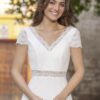 Vue de face d'une mariée en robe blanche à manches courtes et encolure en V ornée de dentelle délicate