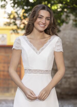 Vue de face d'une mariée en robe blanche à manches courtes et encolure en V ornée de dentelle délicate