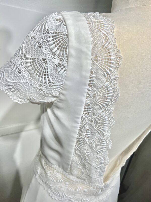 Vue de face d'une mariée en robe blanche à manches courtes et encolure en V ornée de dentelle délicate