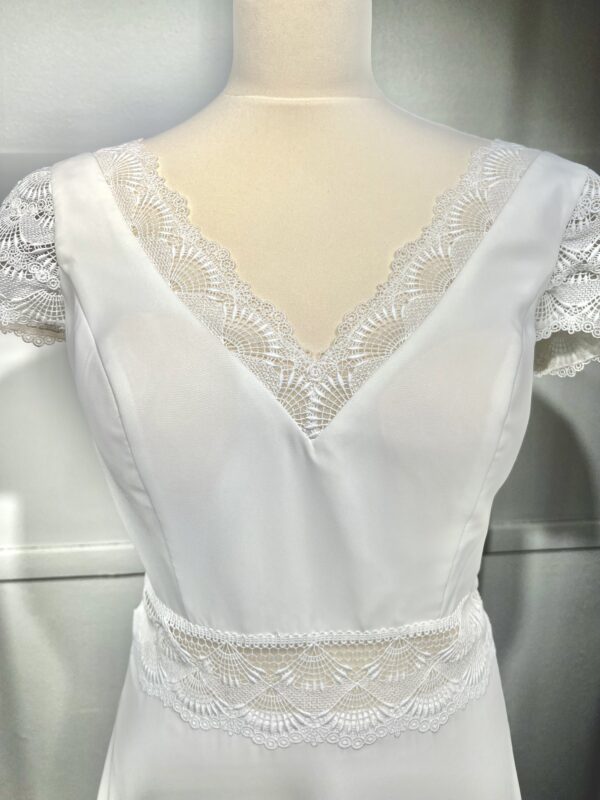 Vue de face d'une mariée en robe blanche à manches courtes et encolure en V ornée de dentelle délicate