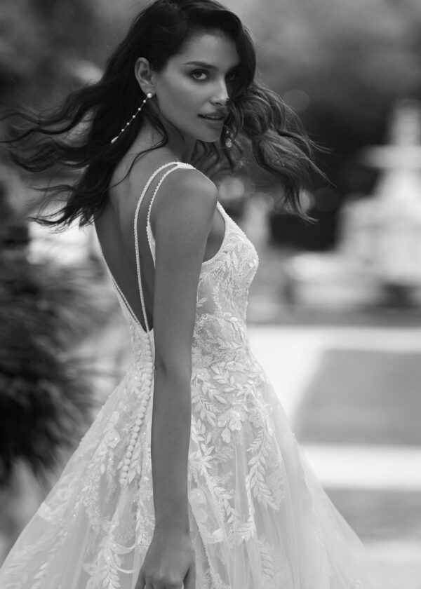 Portrait noir et blanc d'une mariée en robe de mariée, avec un corsage en dentelle et des boucles flottantes, créant une ambiance élégante