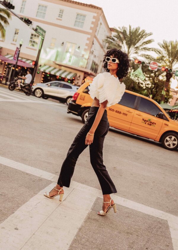 Femme en sandales dorées marchant avec style dans un cadre urbain moderne.