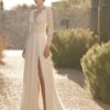 Vue de face d'une mariée portant une robe fluide avec des manches longues en dentelle délicate et un décolleté en V plongeant