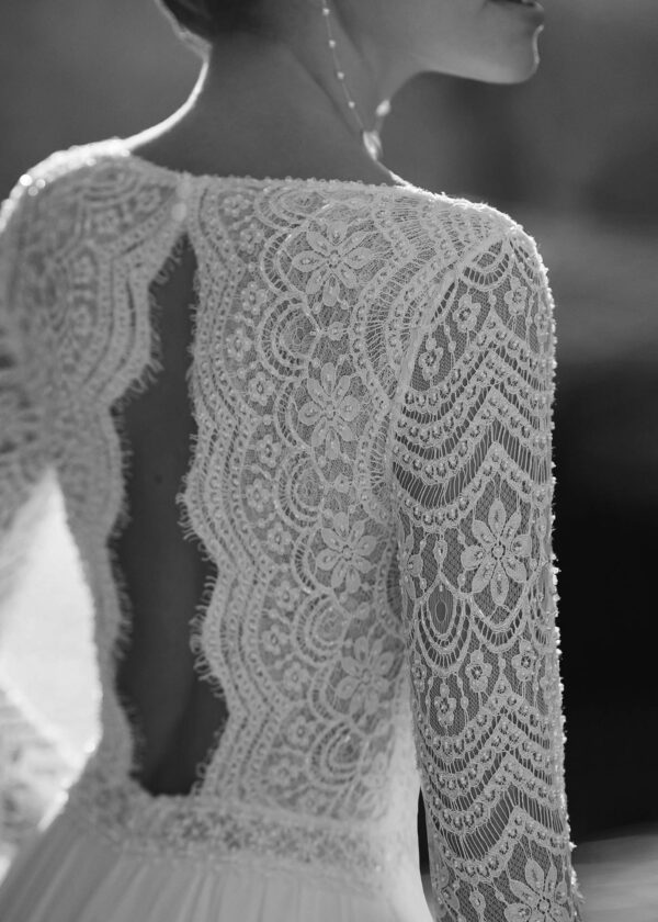 Gros plan sur le motif en dentelle florale des manches longues d'une robe de mariée élégante