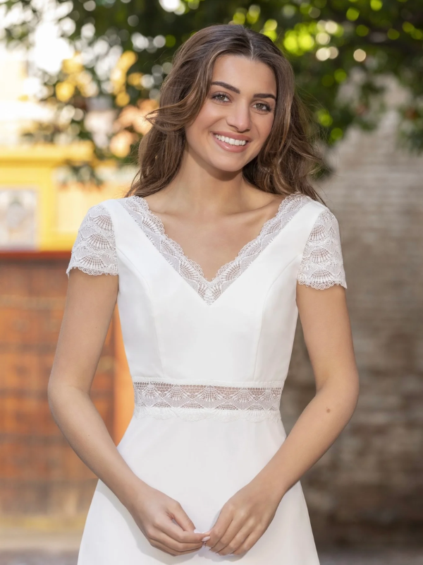 Vue de face d'une mariée en robe blanche à manches courtes et encolure en V ornée de dentelle délicate