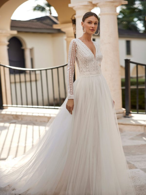 Robe de mariée en tulle fluide avec un haut délicatement brodé à manches longues, capturée sous une lumière naturelle - Rosa Clara