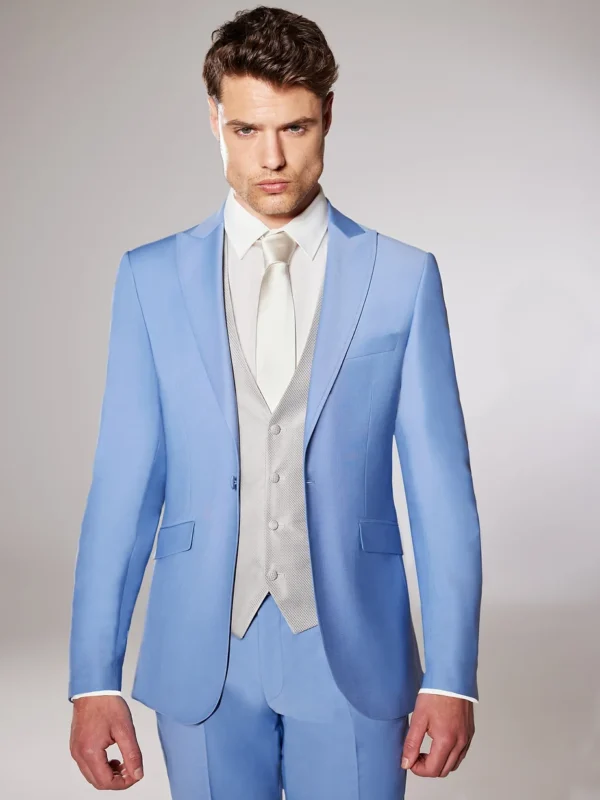 Homme vêtu d’un costume bleu ciel lumineux, complété par un gilet gris perle et une cravate ivoire, sur un fond neutre et épuré.