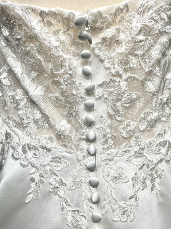 Mariée en robe de mariée classique avec manches bouffantes en tulle, posant dans un jardin luxuriant