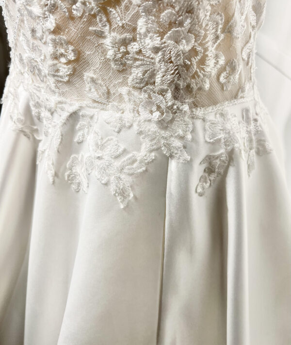Mariée en robe de mariée classique avec manches bouffantes en tulle, posant dans un jardin luxuriant