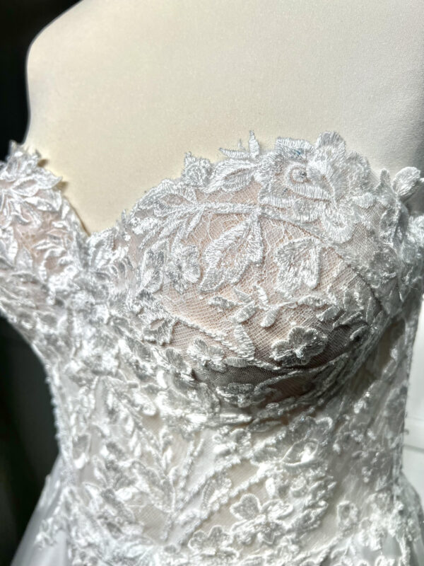 Mariée en robe de mariée classique avec manches bouffantes en tulle, posant dans un jardin luxuriant