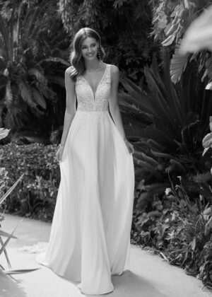 Robe de mariée élégante avec un décolleté en V et une jupe fluide dans un cadre naturel luxuriant