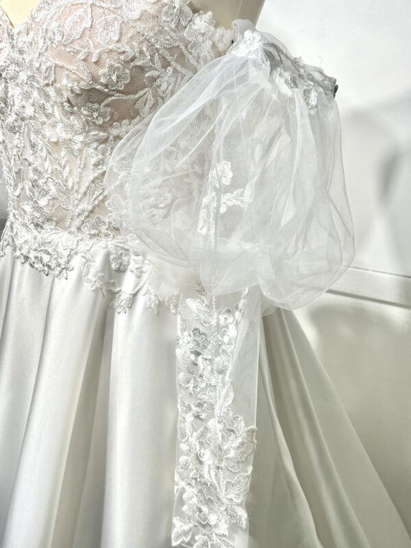 Mariée en robe de mariée classique avec manches bouffantes en tulle, posant dans un jardin luxuriant