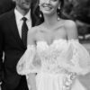 Couple de jeunes mariés souriant, la mariée en robe à manches bouffantes en dentelle, photographie en noir et blanc