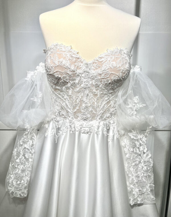 Mariée en robe de mariée classique avec manches bouffantes en tulle, posant dans un jardin luxuriant