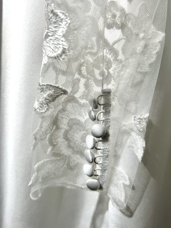 Mariée en robe de mariée classique avec manches bouffantes en tulle, posant dans un jardin luxuriant