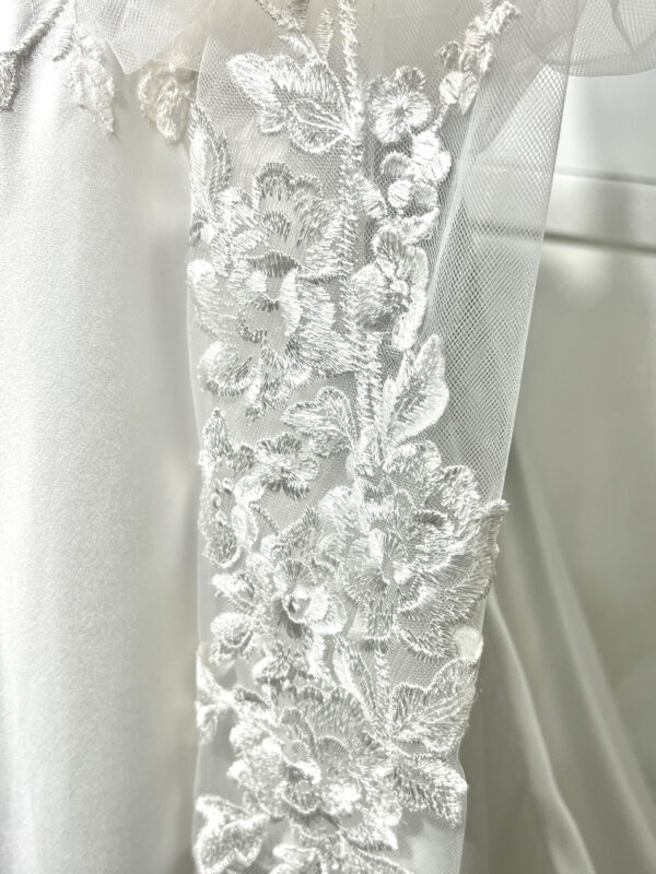 Mariée en robe de mariée classique avec manches bouffantes en tulle, posant dans un jardin luxuriant