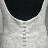Cette robe de mariée allie minimalisme et élégance avec son corsage ajusté à col carré et sa jupe fluide prolongée d’une traîne légère. Son design épuré s’harmonise parfaitement avec un cadre méditerranéen raffiné, idéal pour une mariée au style intemporel.
