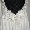 Cette robe de mariée allie raffinement et modernité avec son corsage en dentelle florale et son col haut élégant. Sa jupe fluide crée une silhouette aérienne, sublimée par un décor contemporain. Parfaite pour une mariée en quête de romantisme et de minimalisme.