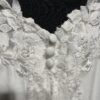 Cette robe de mariée allie raffinement et modernité avec son corsage en dentelle florale et son col haut élégant. Sa jupe fluide crée une silhouette aérienne, sublimée par un décor contemporain. Parfaite pour une mariée en quête de romantisme et de minimalisme.