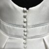 Une robe de mariée princesse avec un col carré structuré et une jupe ample, posant dans une allée bordée d’un château majestueux.