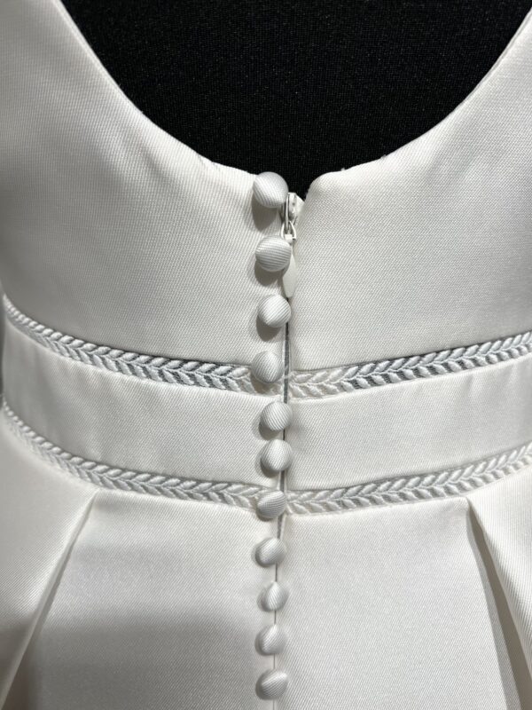 Une robe de mariée princesse avec un col carré structuré et une jupe ample, posant dans une allée bordée d’un château majestueux.