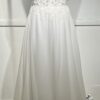 Cette robe de mariée allie raffinement et modernité avec son corsage en dentelle florale et son col haut élégant. Sa jupe fluide crée une silhouette aérienne, sublimée par un décor contemporain. Parfaite pour une mariée en quête de romantisme et de minimalisme.