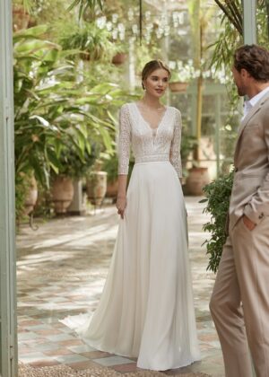 Robe de mariée bohème à manches longues en dentelle dans un jardin intérieur verdoyant