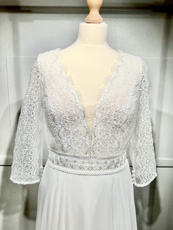Robe de mariée bohème à manches longues en dentelle dans un jardin intérieur verdoyant