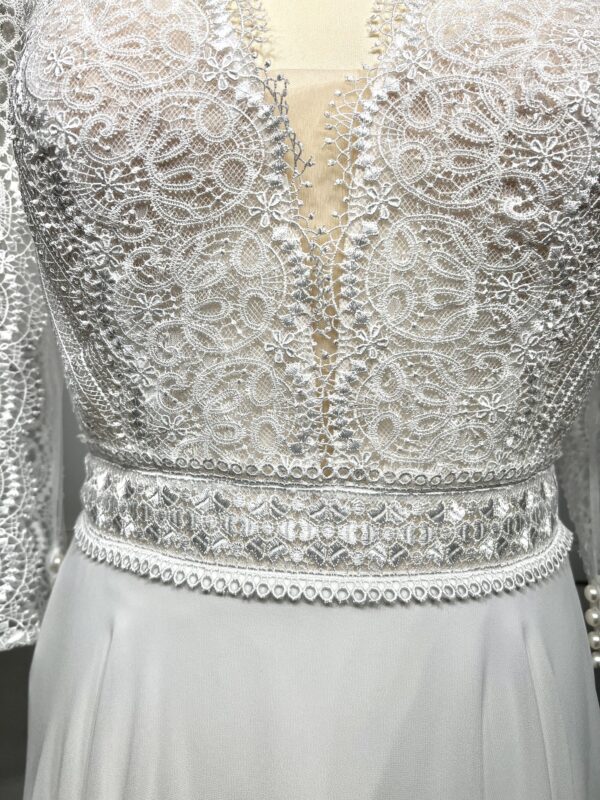 Robe de mariée bohème à manches longues en dentelle dans un jardin intérieur verdoyant